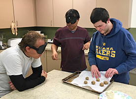 Three students bake cookies in the training centers kitchen